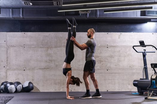 A muscular man assisting a fit woman in a modern gym as they engage in various body exercises and muscle stretches, showcasing their dedication to fitness and benefiting from teamwork and support.