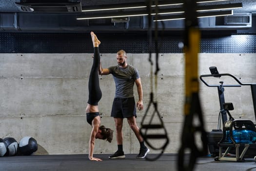 A muscular man assisting a fit woman in a modern gym as they engage in various body exercises and muscle stretches, showcasing their dedication to fitness and benefiting from teamwork and support.