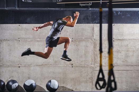 A muscular man captured in air as he jumps in a modern gym, showcasing his athleticism, power, and determination through a highintensity fitness routine.