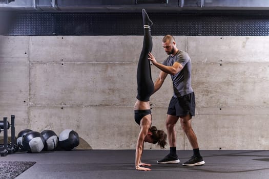 A muscular man assisting a fit woman in a modern gym as they engage in various body exercises and muscle stretches, showcasing their dedication to fitness and benefiting from teamwork and support.