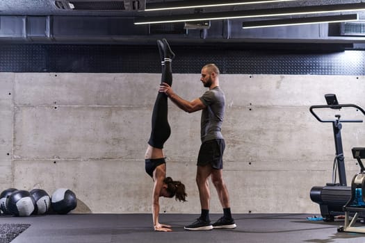 A muscular man assisting a fit woman in a modern gym as they engage in various body exercises and muscle stretches, showcasing their dedication to fitness and benefiting from teamwork and support.