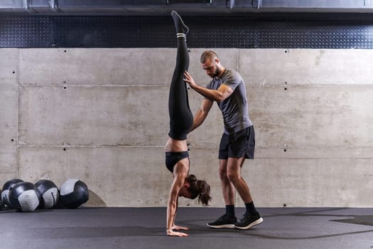 A muscular man assisting a fit woman in a modern gym as they engage in various body exercises and muscle stretches, showcasing their dedication to fitness and benefiting from teamwork and support.