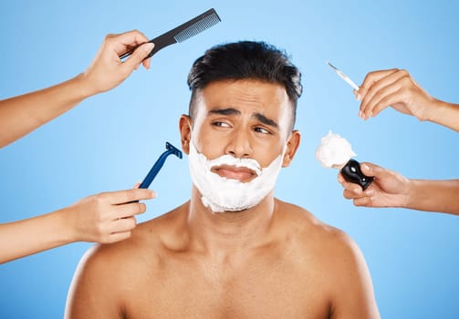 Face, shave and grooming with hands holding equipment for shaving or brushing hair in studio on a blue background. Skincare, wellness and luxury with an unhappy male customer at the barber for beauty.