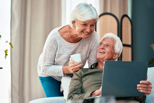 Senior couple, laptop and happy at. home on lounge sofa talking and reading online for online shopping, social media or savings on banking website. Old man and woman together with coffee and wifi.