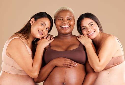 Portrait, beauty and happy with pregnant friends in studio on a beige background for diversity or motherhood. Family, love and pregnancy with a woman friend group showing their baby bump stomach.