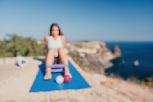 Middle aged well looking woman with black hair doing Pilates with the ring on the yoga mat near the sea on the pebble beach. Female fitness yoga concept. Healthy lifestyle, harmony and meditation.