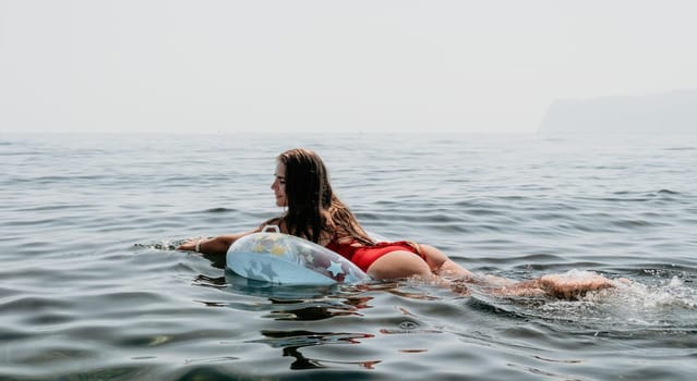 Woman summer sea. Happy woman swimming with inflatable donut on the beach in summer sunny day, surrounded by volcanic mountains. Summer vacation concept