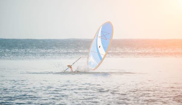 Asian man swimming in sea water and paddleboarding passing beautiful sea at summer sunset. Healthy strong male enjoy outdoor active lifestyle and water sports on holiday vacation