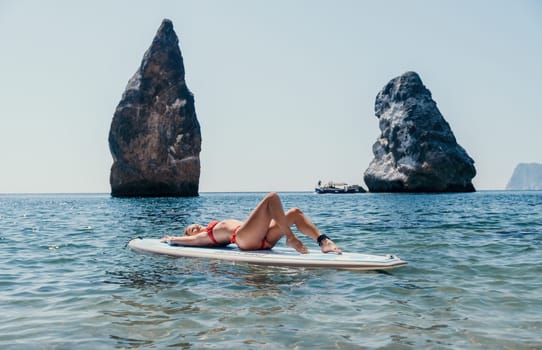 Close up shot of beautiful young caucasian woman with black hair and freckles looking at camera and smiling. Cute woman portrait in a pink bikini posing on a volcanic rock high above the sea