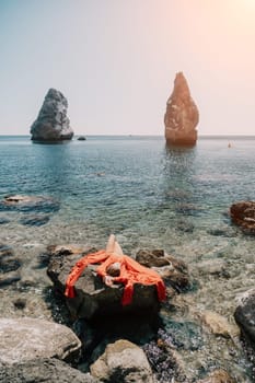 Woman travel sea. Young Happy woman in a long red dress posing on a beach near the sea on background of volcanic rocks, like in Iceland, sharing travel adventure journey