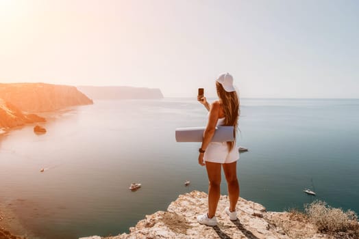 Young woman with black hair, fitness instructor in pink sports leggings and tops, doing pilates on yoga mat with magic pilates ring by the sea on the beach. Female fitness daily yoga concept