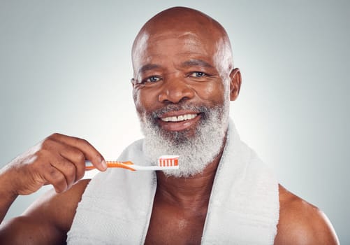 Black man brushing teeth, smile and toothbrush, mouth care and fresh breath, hygiene isolated on studio background. Health, wellness and cleaning with dental portrait, senior person and retirement.