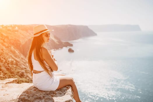 Successful business woman in yellow hat working on laptop by the sea. Pretty lady typing on computer at summer day outdoors. Freelance, travel and holidays concept.