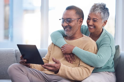 Old couple, tablet and relax with hug on sofa, social media or streaming movie. Love, retirement and elderly man and woman hugging or embrace on couch in living room while internet browsing on tech