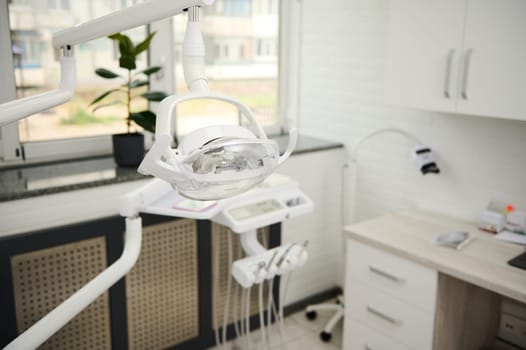 Selective focus on a dental operating lamp with directional LED light. Interior of new modern dental clinic office. Dentistry, medicine, medical equipment and stomatology concept. Medical equipment