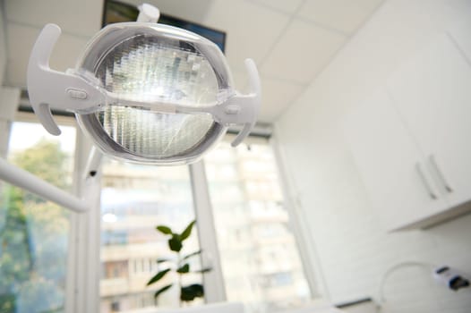 Dental equipment. A dental lamp with directional LED light in the light white interior of a modern dentistry clinic. Operating lamp. Surgical lamp. Health care and medicine. Copy advertising space