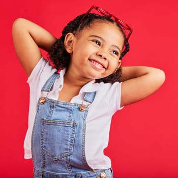 Little girl, happy and thinking in fashion pose, trendy or cool style clothes on isolated red background for kids branding. Smile, youth and child stretching arms in playful, funny and goofy posing.