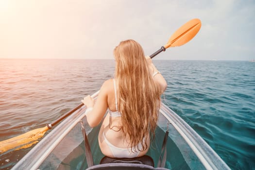 Woman in kayak back view. Happy young woman with long hair floating in transparent kayak on the crystal clear sea. Summer holiday vacation and cheerful female people having fun on the boat.