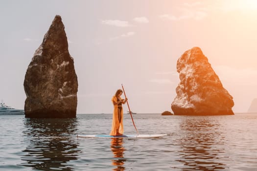 Close up shot of beautiful young caucasian woman with black hair and freckles looking at camera and smiling. Cute woman portrait in a pink bikini posing on a volcanic rock high above the sea