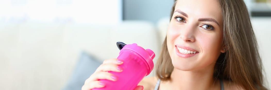 Portrait of sporty smiling beautiful woman with bottle of water. Sports and fat intake during exercise