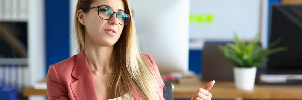 Stylish businesswoman in glasses talking to colleague at workplace. Talking to partner or going through a job interview