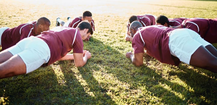 Man, team and plank on grass field for sports training, fitness and collaboration in the outdoors. Group of sport rugby players in warm up exercise together for teamwork preparation, match or game.