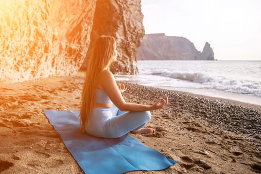 Middle aged well looking woman with black hair doing Pilates with the ring on the yoga mat near the sea on the pebble beach. Female fitness yoga concept. Healthy lifestyle, harmony and meditation.