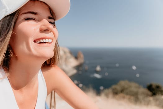 Woman travel sea. Young Happy woman in a long red dress posing on a beach near the sea on background of volcanic rocks, like in Iceland, sharing travel adventure journey