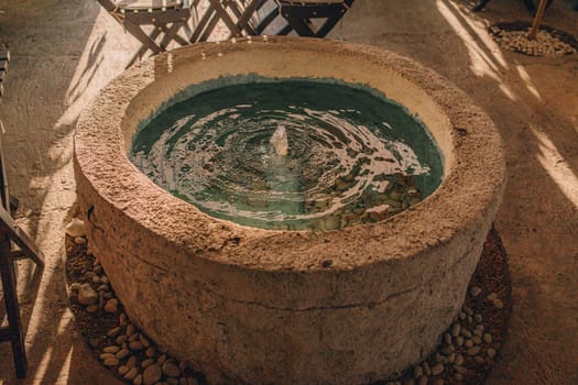 Balinese decorative garden stone basin with water. Tropical outdoor fountain decor, garden wash basin