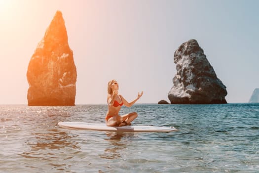 Close up shot of beautiful young caucasian woman with black hair and freckles looking at camera and smiling. Cute woman portrait in a pink bikini posing on a volcanic rock high above the sea