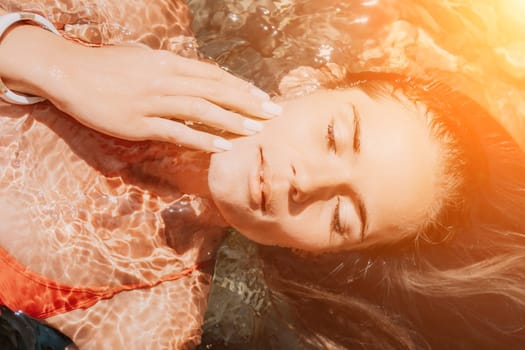 Side view a Young beautiful sensual woman in a mint long dress posing on a volcanic rock high above the sea during sunset. Girl on the nature on overcast sky background. Fashion photo