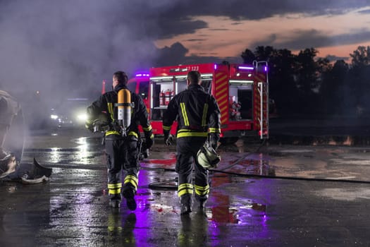 Brave Firefighters Team Walking to the Camera. In Background Paramedics and Firemen Rescue Team Fight Fire in Car Accident, Insurance and Save Peoples Lives concept. High quality photo