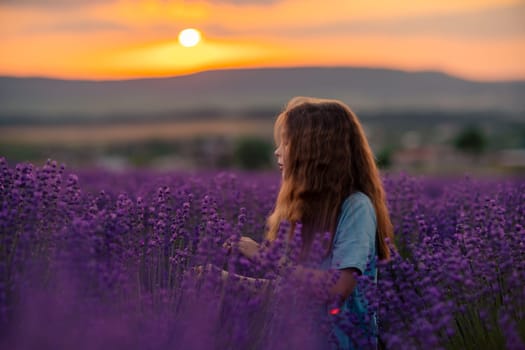 Girl lavender sunset. Girl in blue dress with flowing hair walk on the lavender field