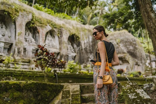 Close up shot of young lady tourist on Gunung kawi temple background. Historical ancient royal tombs attraction