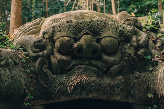 Stone sculpture of a balinese god face with monkeys temple entrance.