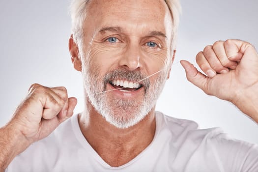 Face, dental floss and senior man in studio isolated on a gray background. Portrait, cleaning and elderly male model with product flossing teeth for oral wellness, tooth care and healthy gum hygiene.