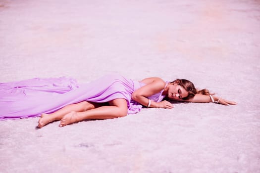 A woman in a pink dress lies on the shore of a pink lake, takes a photo for memory and leaves unforgettable memories