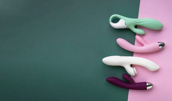 Collection of different types of sex toys on a green and pink background. Sex toys for adults, dildos, vibrators, clitoral stimulators..