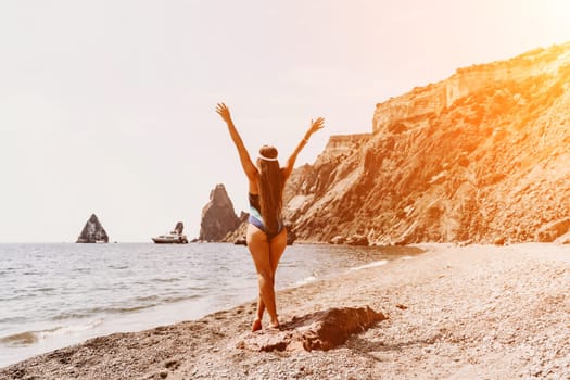 Woman beach vacation photo. A happy tourist in a blue bikini enjoying the scenic view of the sea and volcanic mountains while taking pictures to capture the memories of her travel adventure