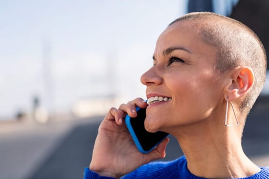 portrait of a confident young woman with buzz cut talking happy on mobile phone, concept or modern lifestyle and technology of communication, copy space for text