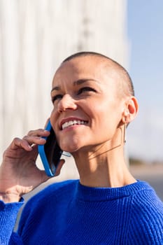portrait of a confident young woman with buzz cut talking happy on mobile phone, concept or modern lifestyle and technology of communication, copy space for text