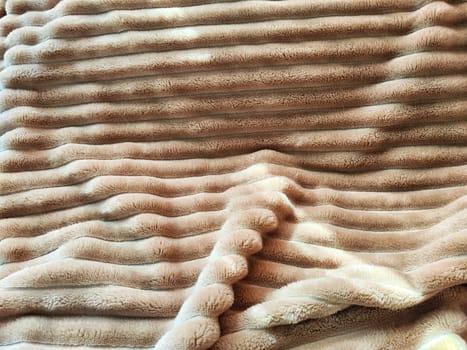 Closeup soft, fluffy sleeping beige blanket or plaid. Crumpled fabric. Abstract background, texture with frame. Partial focus
