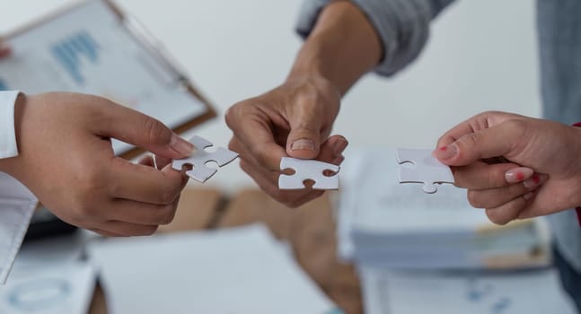 Concept of teamwork and partnership. Hands join puzzle pieces in the office. business people putting the jigsaws team together. Charity, volunteer. Unity, team business.