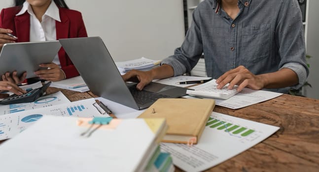 Businesspeople using a calculator to calculate numbers on a company's financial documents, analyzing financial data to plan how to grow the company. Financial concept.