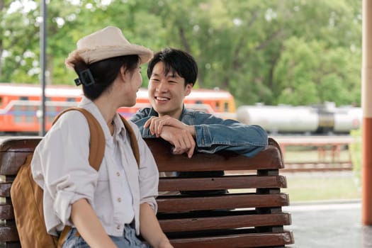 Asian couple chatting while waiting for train to arrive.