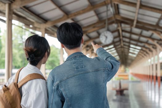 Asian couple travelers, backpack travelers, together at train station platform. tourism activity or railroad trip traveling concept.