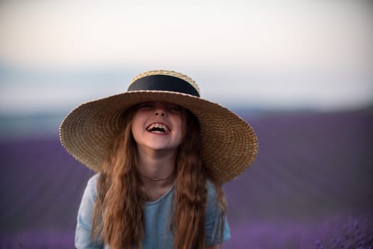 Girl lavender field. Laughing girl in a blue dress with flowing hair in a hat stands in a lilac lavender field.