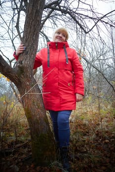 Kirov, Russia - October 23, 2022: Modest shy blonde adult woman with short hairstyle poses for a photo and is embarrassed in autumn park