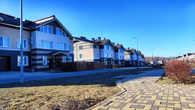 New house on the street in small village or town in spring or atutumn day. Landscape with two-storeyed, building and sunny day with blue sky full of clouds