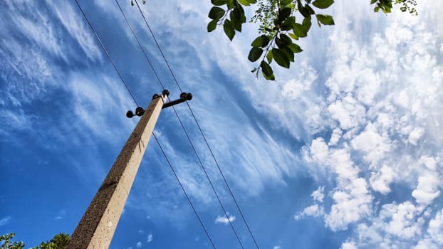 Closeup of old power poles on clear summer day. Old hight voltage electric pole with wires and blue sky with clouuds on background